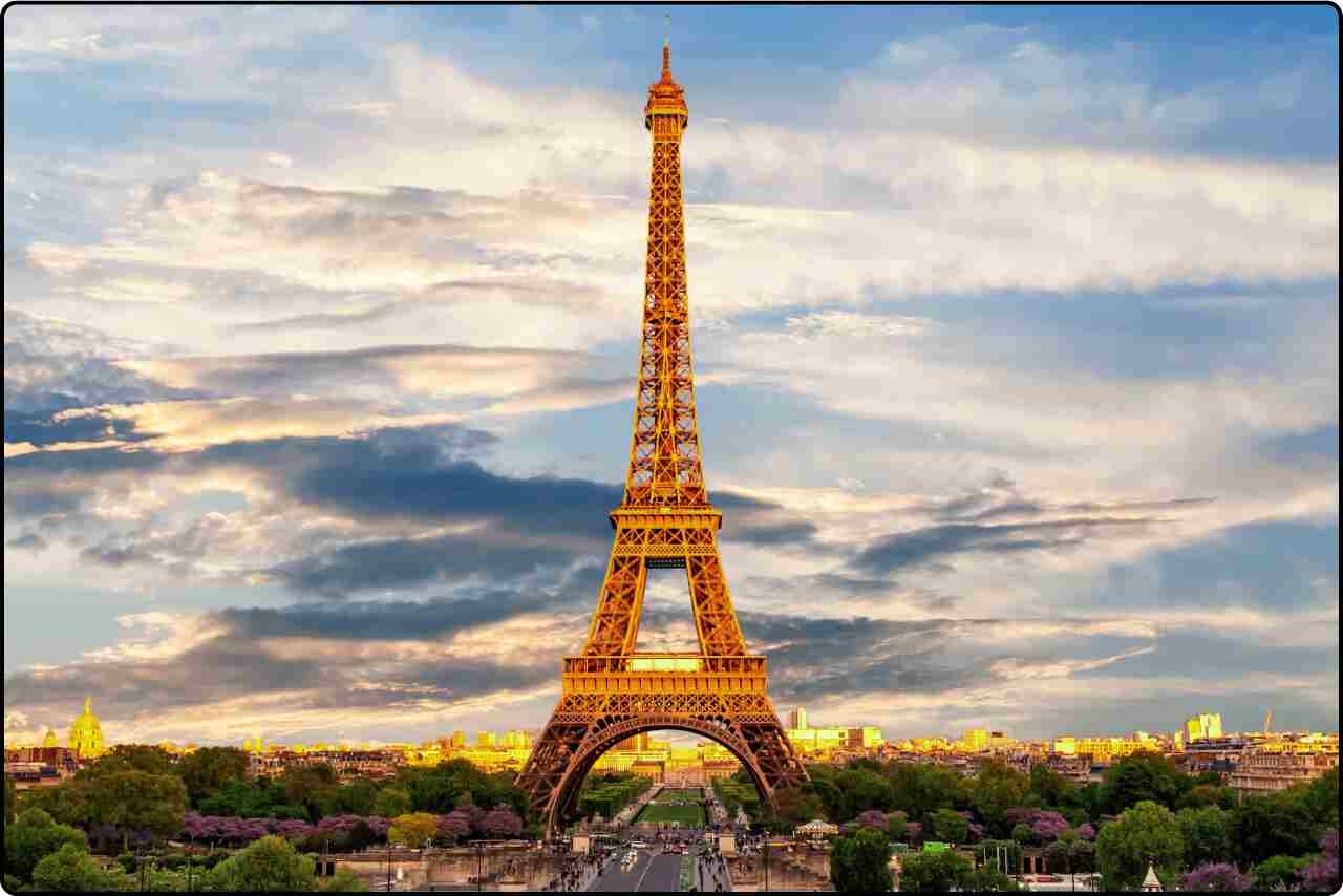 The majestic Eiffel Tower against a blue sky, with fluffy white clouds.